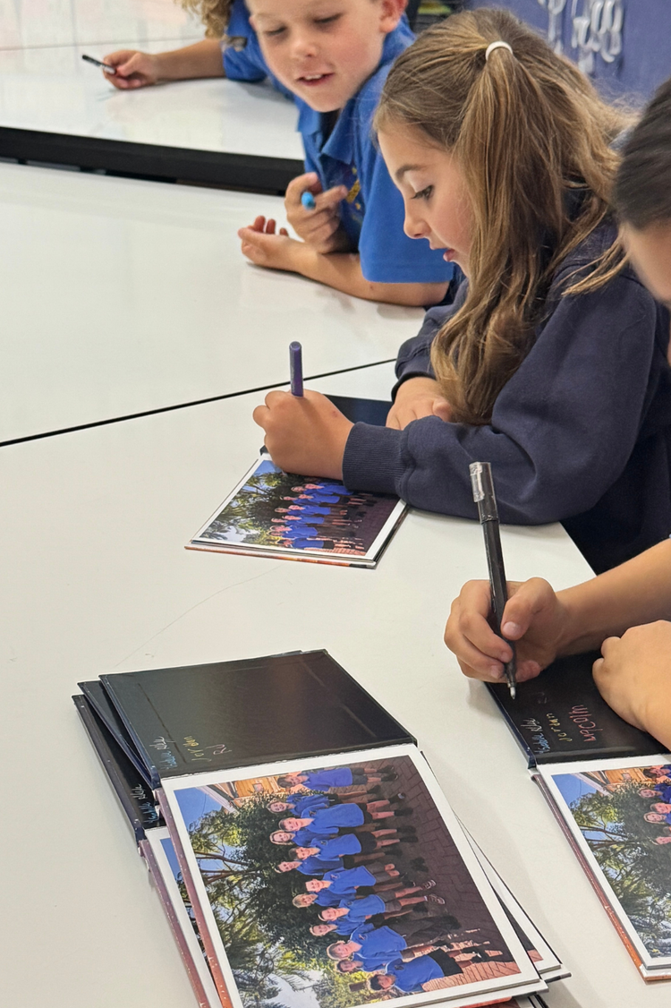 students signing the book that they wrote as part of class
