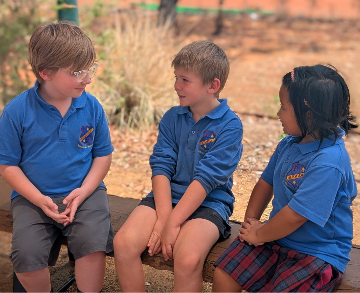 three students sitting in the yarning circle talking