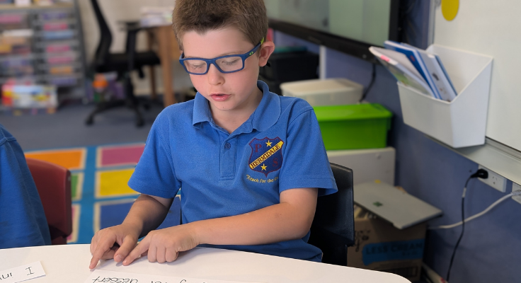 a student in class showing his teacher his reading