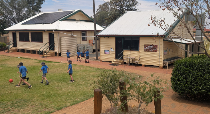 a birdseye view of HPS school with students playing on the grass with buildings in the background